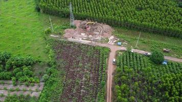 vue aérienne des excavatrices travaillent sur les fondations des pylônes à haute tension et les jambes des poteaux à haute tension. vue de dessus de la construction de lignes électriques dans la forêt. video