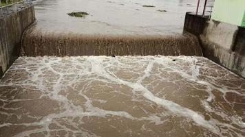 antenne visie van de water vrijgelaten van de beton moeders afvoer kanaal net zo de overloop in de regenachtig seizoen. top visie van troebel bruin Woud water stromen van een dam in landelijk noordelijk Thailand. video