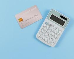 endecha plana de calculadora azul y tarjeta de crédito sobre fondo azul. concepto de negocios y finanzas. foto