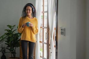 An African American woman uses a laptop, smartphone, tablet and music headset in her home to relax. photo