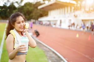 mujer joven relajándose después del entrenamiento físico en el estadio de fútbol. ella tiene una hermosa sonrisa. foto