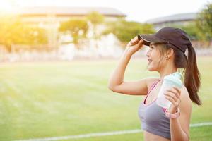 mujer joven relajándose después del entrenamiento físico en el estadio de fútbol. ella tiene una hermosa sonrisa. foto