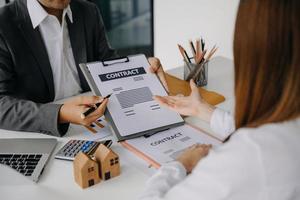 Real estate broker agent presenting and consult to customer to decision making sign insurance form agreement, home in office photo