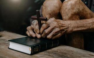 anciano sentado y estudiando las escrituras. la cruz de madera en las manos. conceptos de educación cristiana las sagradas escrituras abiertas
