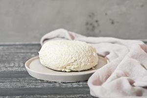 Homemade soft white cheese on wooden black background, Home cottage cheese making. goat milk cheese on grey cement plate. photo