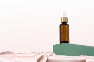 amber glass bottle with dropper or pipette on a green podium or pedestal, hero shot. female beauty face care and misturizing, collagen solution for skin treatment. photo