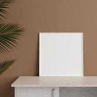 maqueta de marco de póster o foto cuadrada blanca de vista frontal minimalista apoyada contra la pared en la mesa con planta. representación 3d