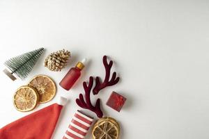 un suero facial o aceite esencial para las vacaciones navideñas en un frasco rojo sobre un fondo blanco con canela y naranjas secas alrededor foto