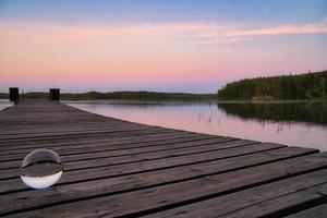 Glass ball on a wooden pier at a Swedish lake at evening hour. Nature Scandinavia photo