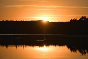 Sunset with reflection on a Swedish lake in Smalland. Romantic evening mood photo