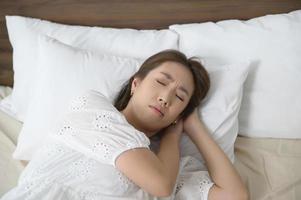 joven asiática durmiendo en la cama en el dormitorio, feliz concepto de estilo de vida saludable foto