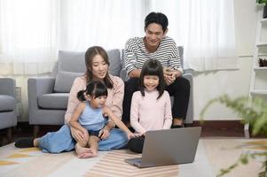 Asian family with children using laptop computer at home photo