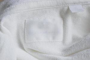 Blank white clothes label on new cotton shirt background photo