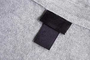 Blank black laundry care clothing label on fabric texture photo