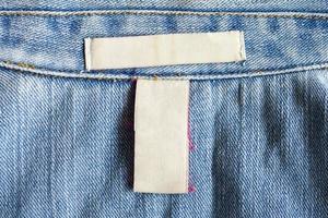 Blank white laundry care clothing label on denim jeans texture background photo