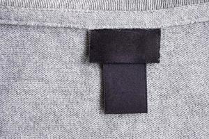 Blank black laundry care clothing label on fabric texture photo