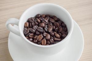 fresh roasted coffee beans in white cup on wood table photo