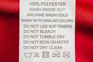 White laundry care washing instructions clothes label on red jersey polyester sport shirt photo