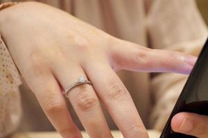 cerrar el anillo de diamantes en el dedo de la mujer usando el teléfono inteligente