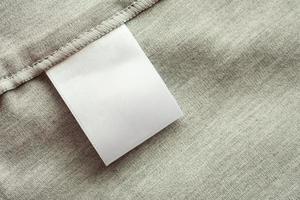 White blank laundry care clothing label on gray fabric texture background photo