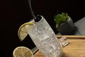 Tom Collins cocktail in a black background, eco-friendly metal straw photo