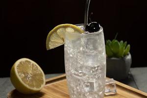 Tom Collins cocktail in a black background, eco-friendly metal straw photo