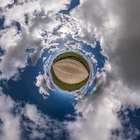 tiny planet in blue sky with beautiful clouds. Transformation of spherical panorama 360 degrees. Spherical abstract aerial view. Curvature of space. photo