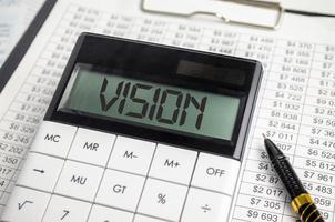 vision word on calculator display and pen, charts and documents photo