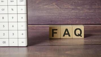 FAQ word on wooden block on top of wooden background. photo