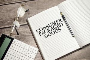 CPG - Consumer Packaged Goods concept words on notepad and calculator and wooden background photo