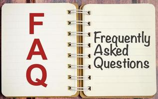 FAQ frequently asked questions text on notebook on wooden desk photo