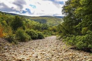 lecho seco del río atravesando el bosque entre montañas en otoño foto