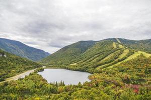 montaña con una estación de esquí frente a un estanque en otoño foto