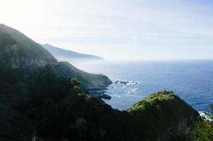 Scenic route landscape view in nature of the Pacific Coast Highway along the Pacific Ocean with green mountains and ocean background photo