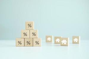 House and property investment, Asset management concept. Inflation, interest rate increase, loan mortgage, house tax, sale discount, home price. Stack of percentage sign and house icon on wood block. photo