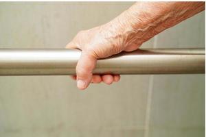 Asian elderly old woman patient use toilet support rail in bathroom, handrail safety grab bar, security in nursing hospital. photo