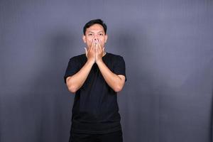 Amazed excited young asian man looking at camera with wow face expression feeling surprised advertising shopping promotion, unbelievable win standing isolated on gray background. photo