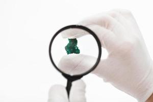 master checks dioptase crystal with magnifier photo