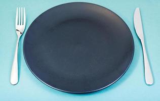 empty black plate with fork and knife set on green photo