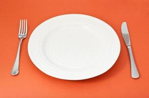 empty white plate with fork and knife on red photo