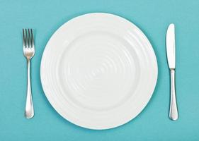 top view of white plate, fork, knife on green photo