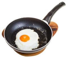 one fried egg in black frying pan isolated photo