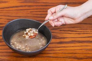 hand holding spoon with beans soup over bowl photo