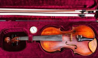 vista superior del viejo violín con arco en caja de terciopelo rojo foto