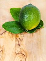 fresh green kaffir lime fruit with leaves on board photo