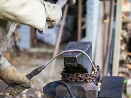 blacksmith forges iron rod on an anvil photo