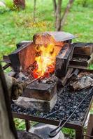 Blacksmith heats iron rod in forging furnace photo