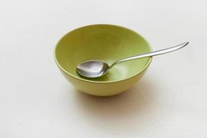 green bowl with spoon on white plaster photo