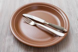 brown plate with parallel knife, spoon on gray photo