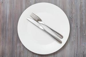 top view of white plate with flatware on gray photo